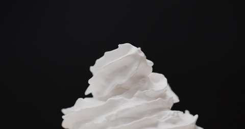 Squeeze whipped cream into a spiral wave. Smooth whipped cream on black background. Zoom in , Food concept.