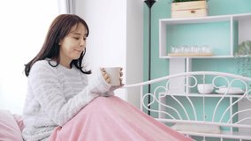 Young Asian woman drinking a cup of coffee in bedroom. - Powered by Shutterstock - Get 15% off with code: PIKWIZARD15