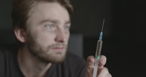 Junkie man holding syringe for drug dose