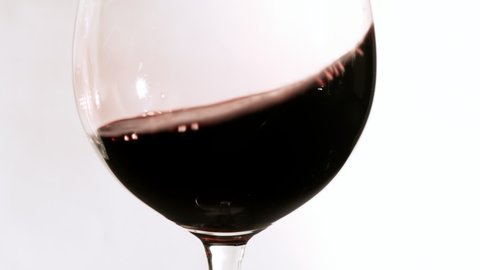 Close up red wine swirling in a goblet wine glass.