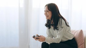 Young Asian woman using a gamepad. Playing video game.
