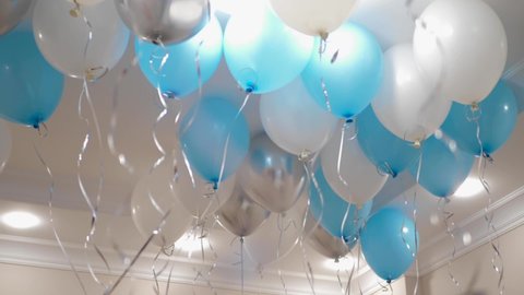 blue and white balloons with helium on the ceiling for a child birthday
