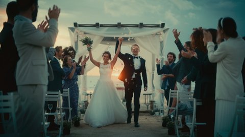 Beautiful Bride and Groom Celebrate Wedding Outdoors on a Beach Near the Ocean at Sunset. Perfect Marriage Venue with Best Multiethnic Diverse Friends Throwing Flower Petals on the Newlyweds.