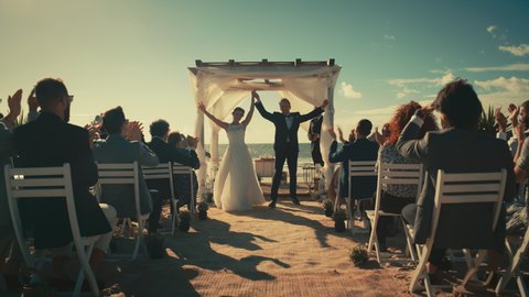 Beautiful Bride and Groom During an Outdoors Wedding Ceremony on an Ocean Beach. Perfect Venue for Romantic Couple to Get Married, Exchange Rings, Kiss and Share Celebrations with Multiethnic Friends.