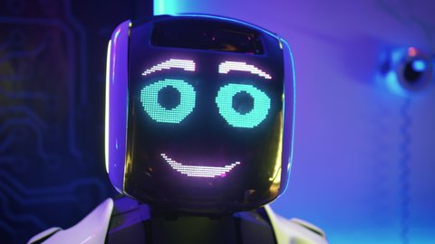 CLOSE-UP: Portrait of a funny robot with a turning head. Device with emotions flirting on camera. Concept of modern technologies.