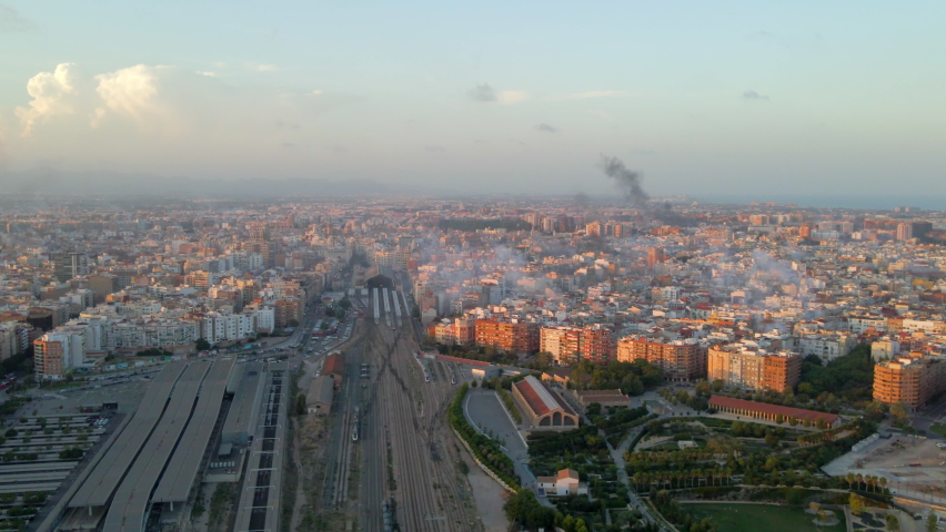 Aerial view of the Valencia train station next to the Central Park. In the background you can see the city with smoke from the Fallas festival and its fireworks.