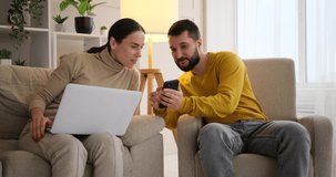 Couple using mobile phone and laptop at home