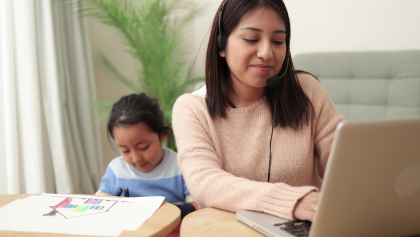 Happy asian mother working on computer at home with her child - Busy family mom giving call center support Royalty-Free Stock Footage #1085347790
