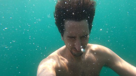 Man face going underwater, person holding breath meditating under water