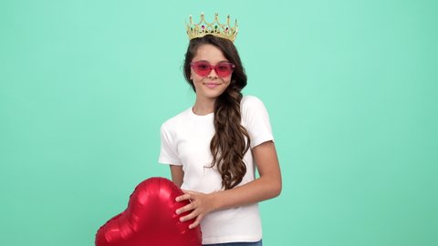 happy teen girl winner in sunglasses and queen crown with heart party balloon, pageant