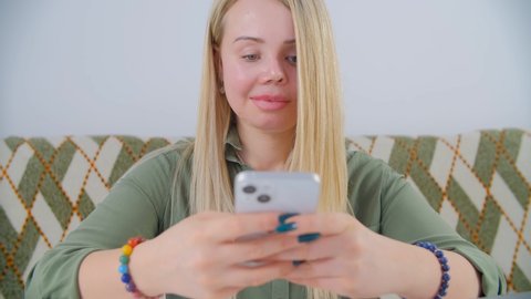 Beautiful blonde white woman with one eye and scars using mobile phone for online communication.Domestic abuse victim living happy life. Violence against women concept. Female with facial scar smiling