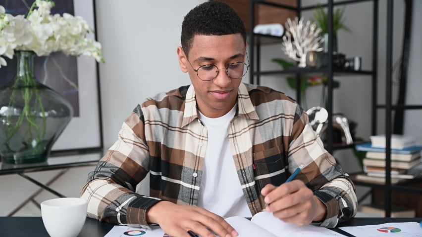 E-learning. Latino smart focused student, listen to an online webinar, seminar, write down information, distance communication, remote learning, gains knowledge, sitting in modern office or at home