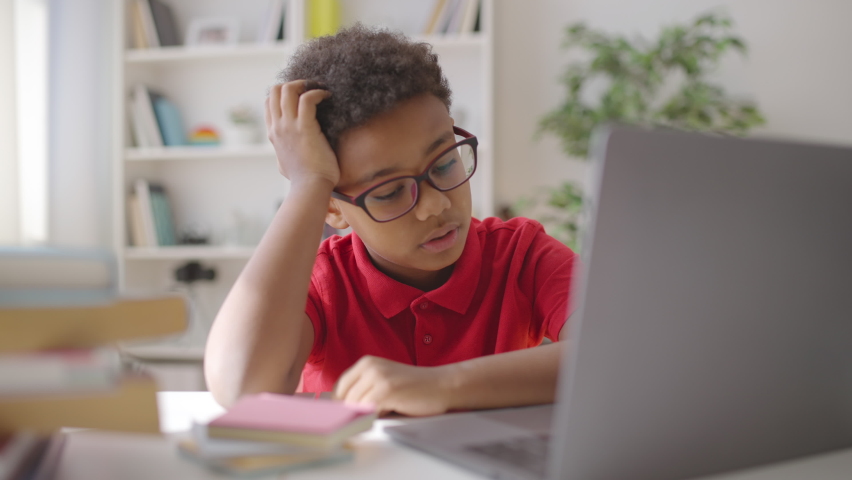 Confused boy in eyeglasses studying online, using laptop at home, difficulties Royalty-Free Stock Footage #1085359232