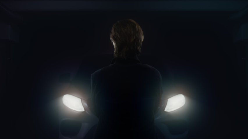 Headlights Illuminated Man Looking Car at Night. Back of a man standing in front of a car with headlights on at night
