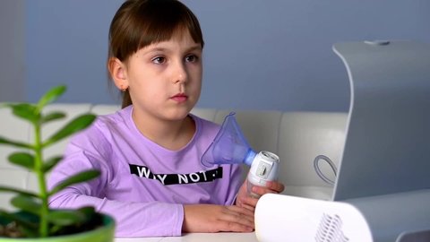 Little girl turn on nebulizer to make inhalation with medical inhaler at home