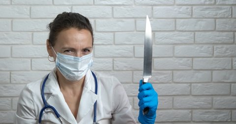 Hold a knife in hospital. A woman doctor in medical uniform hold a steel knife for crazy operations in the cabinet.