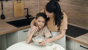 The family spends time in the kitchen. Mother and son. A happy boy kneads the dough. Mom kisses her son. Classes with children at home. Authentic people. what's cooking - Powered by Shutterstock - Get 15% off with code: PIKWIZARD15