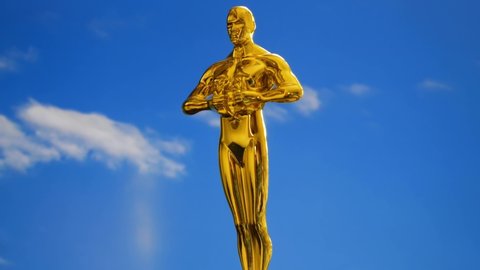 Hollywood Golden Oscar Academy award statue on blue sky with clouds background. Success and victory concept.