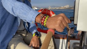 Close-Up of Hands on wheel steering sailing yacht in a sunny day in Alicante.