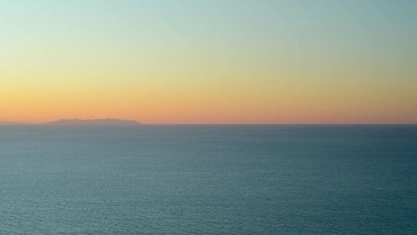 Sunset in the gulf of Baratti, Tuscany Italy with Capraia island in the background. Time lapse with moving water and clouds in winter