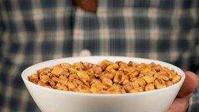 Closeup view 4k stock video footage of white bowl full of tasty crispy organic salted toasted corn seeds. Man eating snacks with great appetite