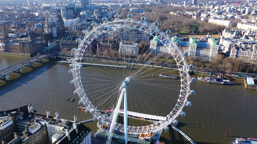London, Westminster | United Kingdom - December 15 2019: Aerial drone video of iconic giant Ferris Wheel of London eye in front of river Thames and houses of Parliament and Big Ben