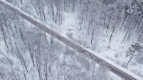 Aerial top down drone shot of Snowy forest and empty road . Forest road from above. White background. Diagonal highway. Minimalism concept 4k video