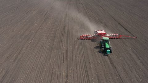 DNIPRO, UKRAINE - MAY 03, 2020: aerial view of tractor with the seeder working at the large field at the windy spring day
