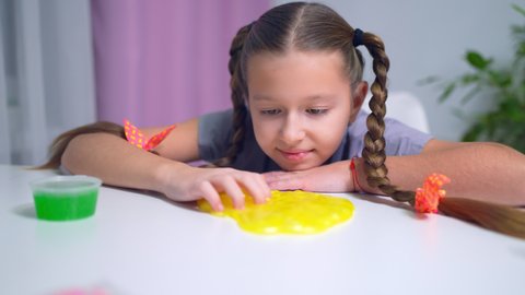 girls playing with yellow shiny slime at the table at home
