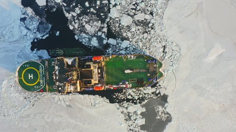 Drone view vertical down of the diesel-electric icebreaker Novorossiysk at anchor among the ice. Ensuring navigation during the laying of a frozen sea channel - JAN 08, 2022 VLADIVOSTOK, RUSSIA