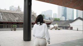 pretty young asian woman in white shirt running in the urban city square enjoy the view exciting travel tour concept at Chengdu China 4k slow motion clip camera follow view