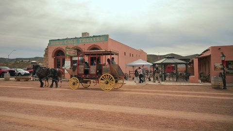 Tombstone , Arizona , United States - 12 22 2021: People and horse carriages pass by the Bird Cage Theatre in Tombstone, Arizona