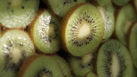 Kiwi fruit. Vertical shot beam of sunlight passes over sliced kiwi fruit in shadow. Close-up