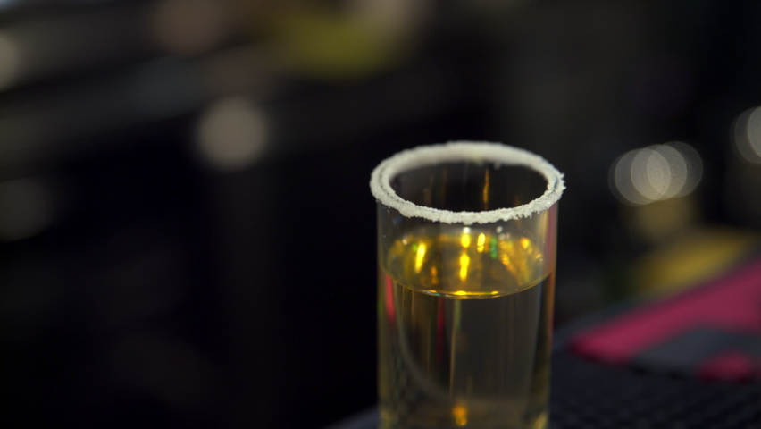 tequila shot glass with lime slice. female hand puts green lime slice on tequila shot, very close-up. strong alcohol portion. alcoholic drink. alcohol consumption. night club drinking party concept Royalty-Free Stock Footage #1085391035