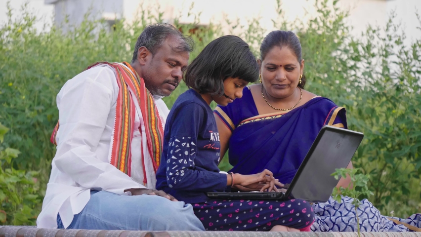 Happy progressive farmer family sitting outdoors on the farm including father, mother, and daughter using a laptop and interacting with each other. Concept of rural Family, relationship and farming Royalty-Free Stock Footage #1085391743