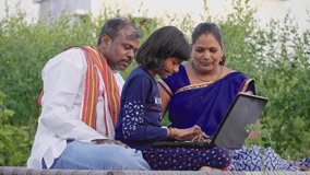 Happy progressive farmer family sitting outdoors on the farm including father, mother, and daughter using a laptop and interacting with each other. Concept of rural Family, relationship and farming - Powered by Shutterstock - Get 15% off with code: PIKWIZARD15