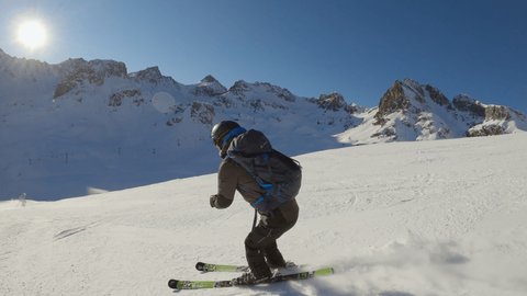 Follow shot, young man skiing downhill on ski slope in the Alps. Action camera filming skier descending technical piste 
