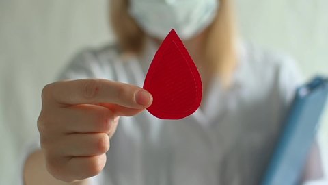 Concept of give blood donation, blood transfusion. Doctor in white coat holds drop of blood on white background. World hemophilia day. World AIDS and hiv day. Copyspace. top view banner. fullhd