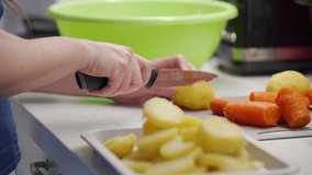 Woman cooking in the kitchen, chop and slice boiled potatoes with knife on kitchen countertop closeup. High quality 4k footage