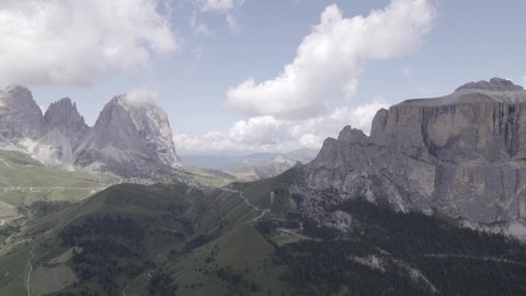 Drone video with frontal plane advancing, over sella pass, with Sassolungo mountain on the horizon.