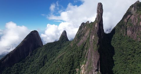 Wide view aerial panoramic landscape of Brazil mountain range Serra dos Orgaos in Teresopolis, Rio de Janeiro with Dedo de Deus, Gods finger, peak in the middle and clouds behind