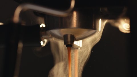 Pouring coffee stream from professional machine in cup. Making double espresso. Flowing fresh ground coffee. Drinking roasted black coffee in the morning. Hot Coffee Drink Concept
