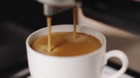 Coffee machine filling a cup with. Making coffee by coffee machine into cup, espresso coffee coming out from an automated coffemaker machine. Beverage drink for breakfast