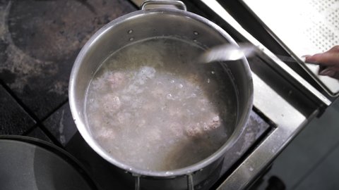 boil meatballs. cooking. close-up. top view. meatballs are boiled in a large saucepan. the cook is stirring the broth. buffet restaurant kitchen
