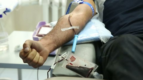 Take blood from volunteers at donor center. The nurse puts a tourniquet on arm, pricks needle into patients arm. Transfusion Machine Collects Blood Plasma