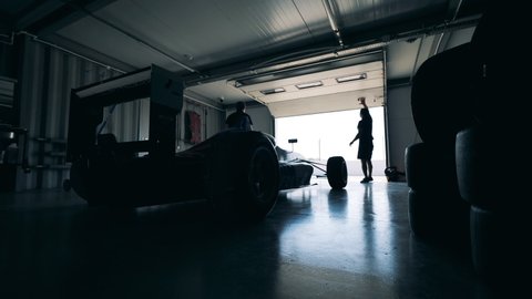 Mechanics are closing garage with a racing car inside