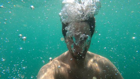 Person under water holding breath. Portrait face submerged underwater