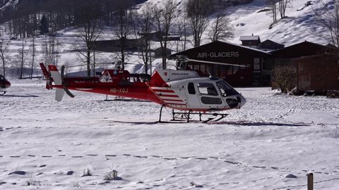 Helicopter of Air Glaciers Eurocopter register HB-XQJ taking off from heliport at mountain valley Lauterbrunnen on a sunny winter day. Movie shot January 15th, 2022, Lauterbrunnen, Switzerland.