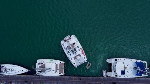 Phuket, Thailand, 19, December, 2019:
Sailboat emerges from bottleneck in dock, sailing catamaran emerges stern in downstream