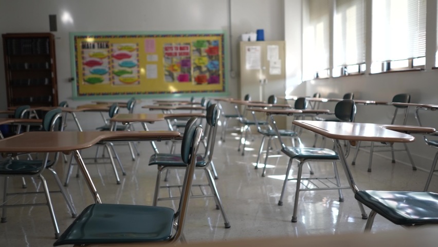 Desks in empty dark high, middle, or elementary school classroom with light coming through windows. Royalty-Free Stock Footage #1085422235